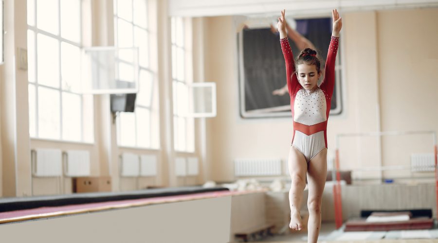 Child gymnastics balance beam. Girl gymnast athlete during an exercise horizontal bar in gymnastics competitions.